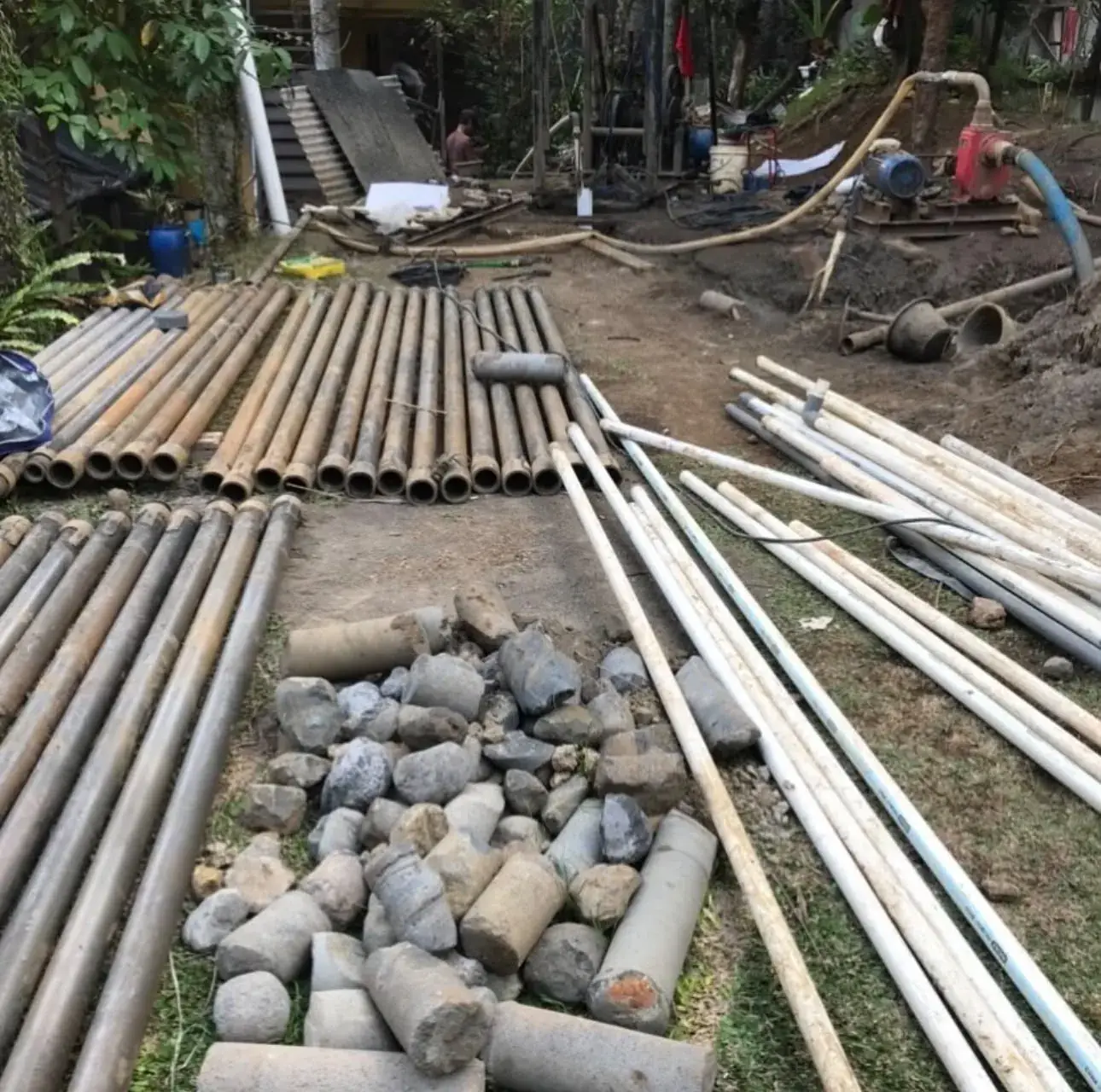 Tumpukan pipa dan casing PVC yang disiapkan di lokasi proyek pengeboran sumur bor